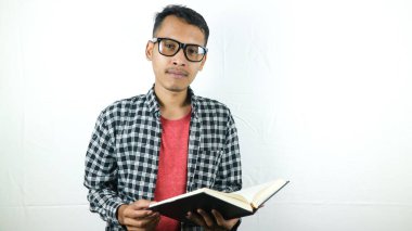 Yakışıklı Asyalı öğrenci gülümsüyor, elinde kitap tutuyor ve okuyor.