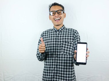 Asyalı bir adamın portresi, gülümseyen bir ifadeyle başparmak kaldırırken büyük boş bir cep telefonu tutuyor. Reklam kavramı