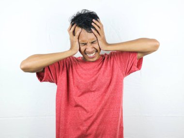 Asyalı insanlar üzgün ve baş ağrısından dolayı ellerini sıkarak başlarını sıkıyorlar. Stres ve migren kavramı.