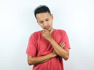 Asyalı adam çeneye dokunuyor, karar veriyor, bir şey seçiyor, şüpheleri var, beyaz arka planda duruyor.