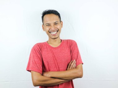 Kolları çapraz kırmızı tişörtlü, gülümseyen yakışıklı Asyalı adam.