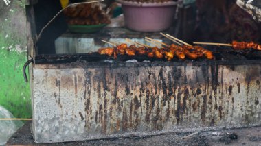 Endonezyalı adam mangal kömürü ve dumanlı tavuk ızgara satay, iştah açıcı bir görünüm ile.