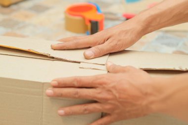 Birisi karton, baloncuk ambalajı ve koli bandı kullanarak paket paketliyor. Mal teslim süreci.