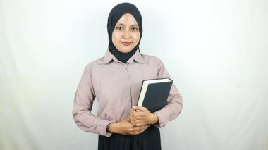 Gülümseyen Asyalı Müslüman öğrenci elinde kitapla beyaz arka planda izole edilmiş kameraya bakıyor. Lise konseptine geri döndüm.