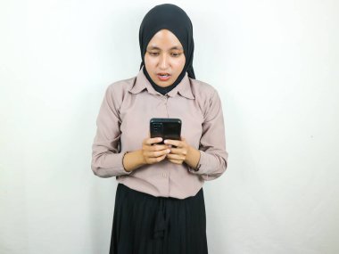 Akıllı bir telefon ekranına bakarken tesettürlü genç bir Asyalı kadının şaşırmış ifadesi