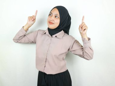 Tesettürlü güzel Asyalı Müslüman kadın, fotokopi uzayı göstererek gülümsüyor. Reklam kavramı