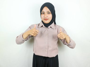 tesettürlü gülümseyen Asyalı müslüman kadın başparmağını göstererek onaylıyor, tavsiye ediyor, sanki iyi bir şeymiş gibi.