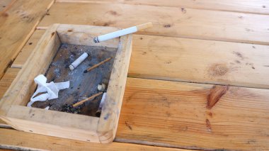 Sigara ve kül tablası ahşap bir masada.