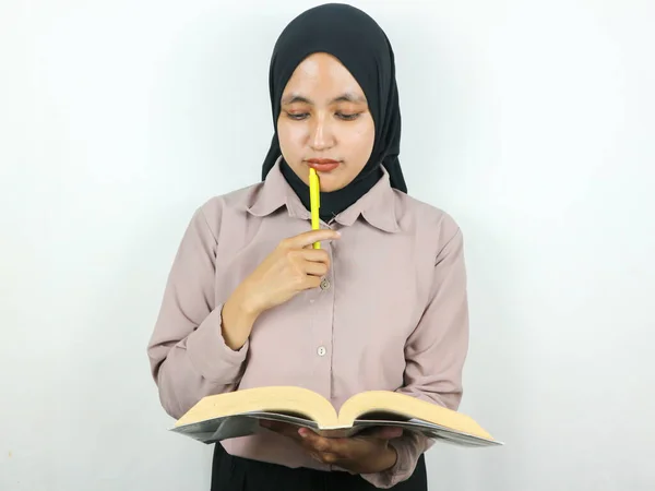 Portrait beautiful Asian woman in hijab holding book and pen, thinking about something isolated on white background. Back to school in high school college concept