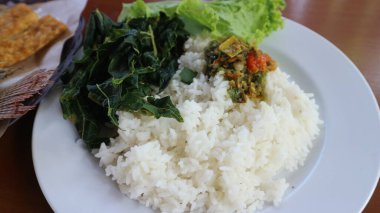 Beyaz pirinç, acı sos ve sebzeli kızarmış Tilapia Balığı (Lalapan Nila Goreng) Endonezya halkı arasında çok popüler bir yemektir..