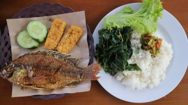 Beyaz pirinç, acı sos ve sebzeli kızarmış Tilapia Balığı (Lalapan Nila Goreng) Endonezya halkı arasında çok popüler bir yemektir..