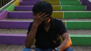 Açık havada merdivenlerde oturan genç adam vurguladı