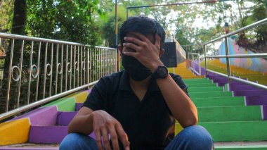 Açık havada merdivenlerde oturan genç adam vurguladı