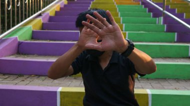 Merdivenlerde oturan genç adam, şiddeti bırak. Uyarı, yasaklama, inkar