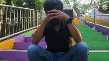 Açık havada merdivenlerde oturan genç adam vurguladı