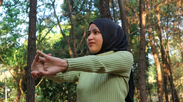 Müslüman kadınlar egzersiz yaparken kollarını uzatıyor ve çam ağaçlarının ortasında temiz hava soluyor. Egzersiz ve Yaşam Tarzı konsepti. Mutlu bir hayat ve sağlık hizmeti teması. Doğa ve Açık hava teması.