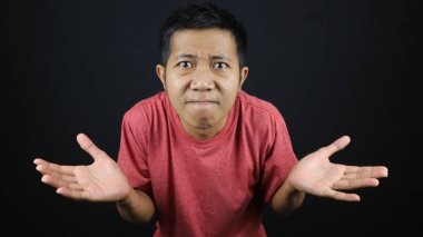 Kırmızı tişörtlü Asyalı adam hiç bir hareket göstermedi, omuz silkti ve elini kaldırdı. Siyah arkaplanda izole