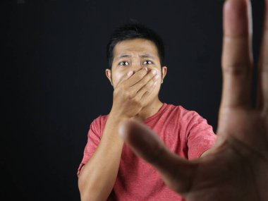 Burnunu kapatan Asyalı bir jest yap ve güçlü bir koku yüzünden eliyle dur işareti yap. Kötü kokuyor. siyah arkaplan