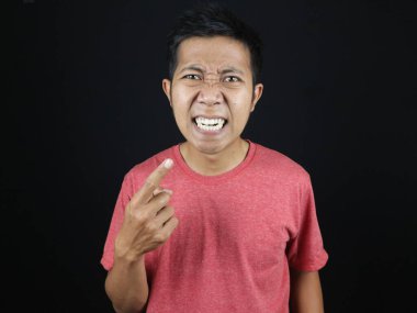 Asyalı adam şaşırmış ve rahatsız olmuş bir ifadeyle dişlerini işaret ediyor.