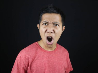 Şaşırmış genç adam, ağzını aç. Siyah arka planda izole edilmiş inanılmaz bir bilgi.