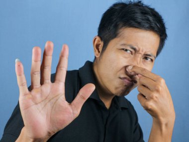 Komik Asyalı adam pis ve iğrenç bir koku alıyor. Dayanılmaz bir koku. Nefesini burnunda tutuyor. Kötü koku konsepti