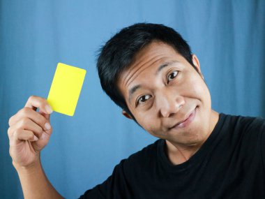 Asyalı adamın mavi arka planda boş kart tutması komik bir yüz ifadesi. Aktarım konsepti