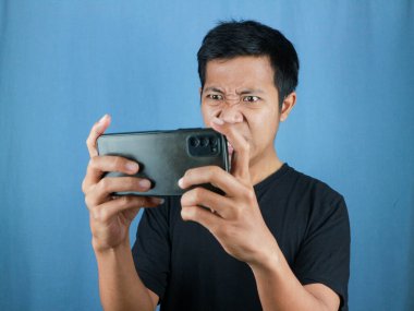 Asyalı adam akıllı telefonuyla mobil oyun oynuyor..