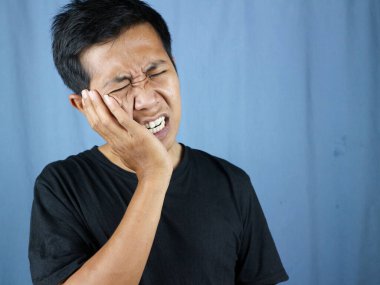 Diş sorunları. Ağrıyan yanağa baskı yapan sağlıksız bir adamın portresi, akut diş ağrısı, periodontal hastalık, çürük ya da çene ağrısı. diş ağrısı kavramı mavi arkaplanda izole edildi