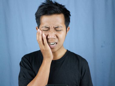 Diş sorunları. Ağrıyan yanağa baskı yapan sağlıksız bir adamın portresi, akut diş ağrısı, periodontal hastalık, çürük ya da çene ağrısı. diş ağrısı kavramı mavi arkaplanda izole edildi