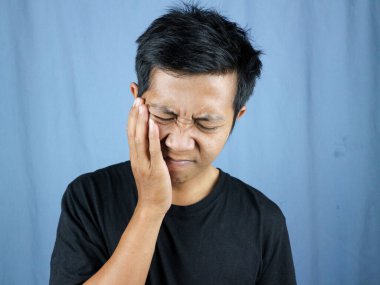 Diş sorunları. Ağrıyan yanağa baskı yapan sağlıksız bir adamın portresi, akut diş ağrısı, periodontal hastalık, çürük ya da çene ağrısı. diş ağrısı kavramı mavi arkaplanda izole edildi