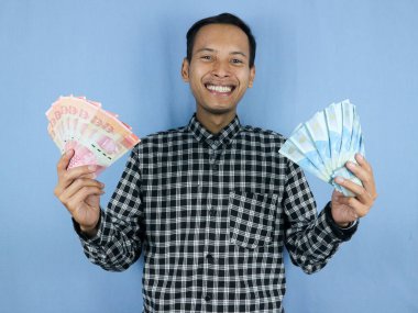 Yakışıklı Asyalı adamın elinde Endonezya 'nın kağıt para banknotları var. İş ve finans kavramı.