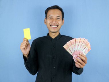 Heyecanlı yüz ifadesi yakışıklı Asyalı adamın elinde boş kart ve para banknotları var. İş ve finans kavramı.