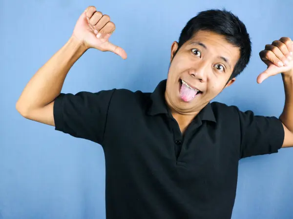 crazy face expression of young asian man smiling looking at camera, isolated on blue background.