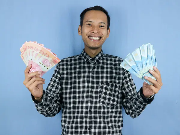 Yakışıklı Asyalı adamın elinde Endonezya 'nın kağıt para banknotları var. İş ve finans kavramı.