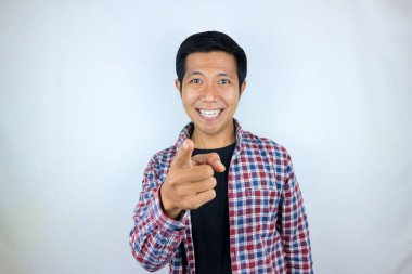 Asyalı adam kameraya bakıp işaret ederken gülümsüyor.