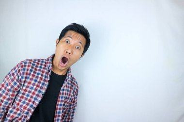 Beyaz arka planda yalıtılmış fanila gömlekli, şaşırmış Asyalı adamın komik ifadesi.