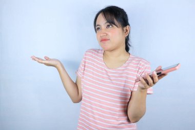 Beyaz arka planda akıllı telefonu tutan Asyalı kadının kafa karıştırıcı ifadesi
