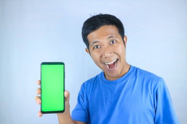 Beyaz arka planda boş bir telefon ekranı gösterirken gülümseyen Asyalı genç adam kameraya bakıyor.