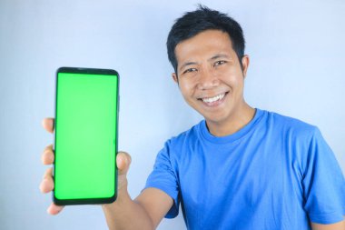 Beyaz arka planda boş bir telefon ekranı gösterirken gülümseyen Asyalı genç adam kameraya bakıyor.