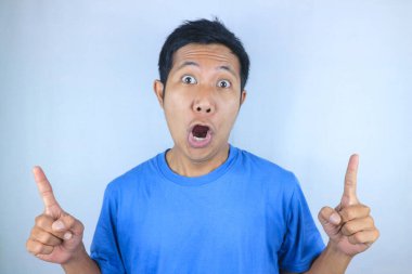 Asyalı genç bir adamın beyaz arka planda izole edilmiş ürünleri tanıtan komik yüz ifadesi.