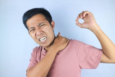 Genç Asyalı adam omzunda acı hissediyor. Halk, sağlık ve tıp konsepti