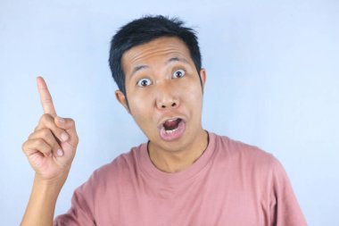 Beyaz arka planda izole edilmiş ürünleri destekleyen Asyalı genç adamın komik yüz ifadesi.