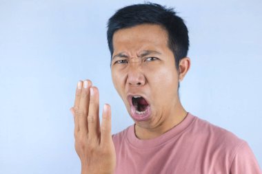 Asyalı adam nefesini eliyle kontrol ediyor. Ağız kokusu kavramı.