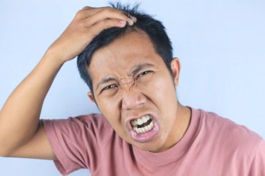 Saçını kontrol ederken kepek sorunu yüzünden Asyalı genç adamın sinirli ve stresli ifadesi