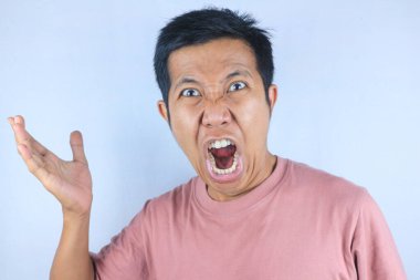 Asyalı adamın kızgın yüz ifadesi güçlü el hareketleri yaparken, beyaz arka planda izole edilmiş.