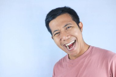 Gülen yüz ifadesi genç Asyalı mutlu bir adam kameraya bakıyor, beyaz arka planda soyutlanmış.