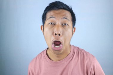 Aptal yüz ifadesi. Genç Asyalı bir adam beyaz arka planda izole edilmiş kameraya bakıyor.