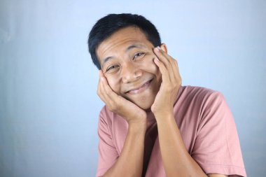 Gülümseyen yüz ifadesi genç Asyalı adam kameraya bakarken mutlu, beyaz arka planda soyutlanmış.