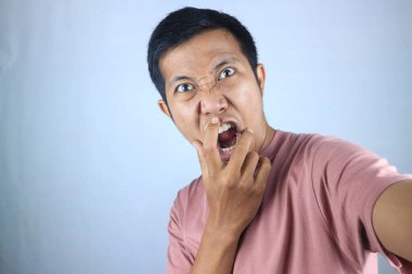 İnançsızlık, kameraya bakan Asyalı genç adamın şok olmuş yüz ifadesi. beyaz arkaplanda izole