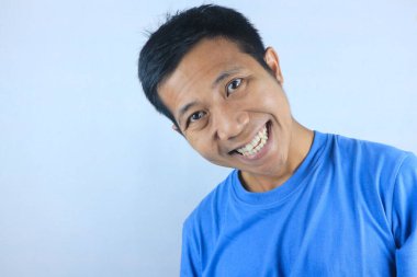 Gülümseyen yüz ifadesi genç Asyalı adam kameraya bakarken mutlu, beyaz arka planda soyutlanmış.